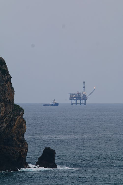 An oil rig beyond a rock formation at sea